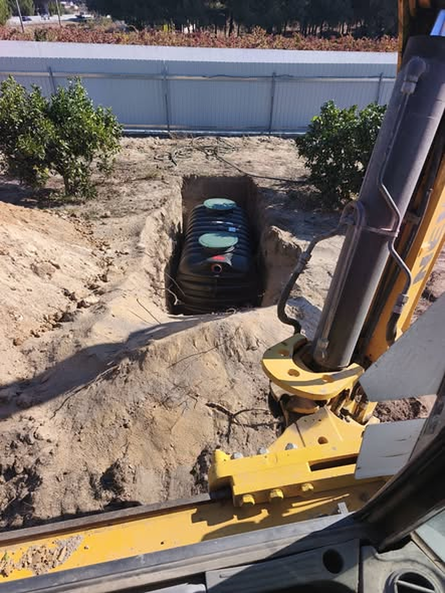 Retroescavadora junto a depósito instalado em vala entre laranjais